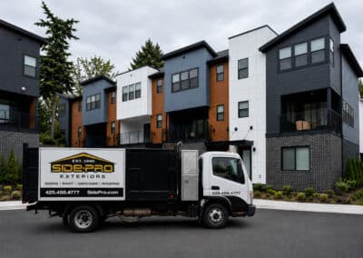 Completed row of modern multi-family townhomes in mixed cladding with a Side-Pro Exteriors truck parked in front