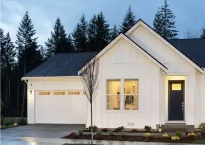 White farmhouse siding at dusk with warm interior lighting
