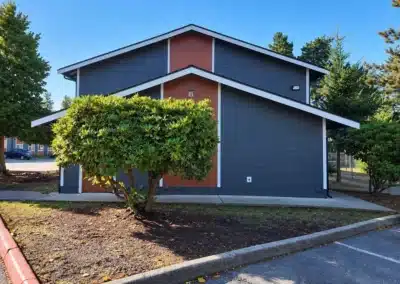 Gable end of an apartment building at Phoenix Court with grey lap siding and a rust panel accent
