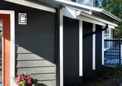 Apartment clubhouse entry with dark lap siding, white trim and a covered walkway